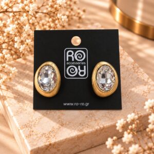 RO Accessories Crystal Oval Elegance χρυσά οβάλ σκουλαρίκια με μεγάλη διάφανη πολυεδρική πέτρα και σατινέ χρυσό περίγραμμα.