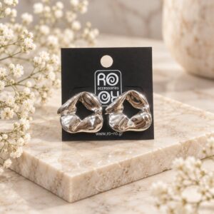 RO Accessories Sculptural Silver ασημί statement σκουλαρίκια με ασύμμετρο γεωμετρικό σχέδιο, ανοιχτό κέντρο και γυαλιστερές μεταλλικές καμπύλες.